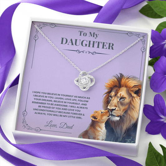 Necklace with lion and cub design on a purple card with text, surrounded by purple ribbon and flowers.